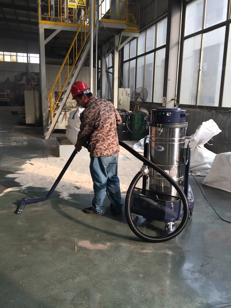 车间工人操作铸造砂子回收用工业吸尘器